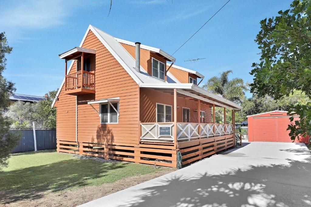 a orange house with a balcony on a street at Aloha Amity in Amity Point