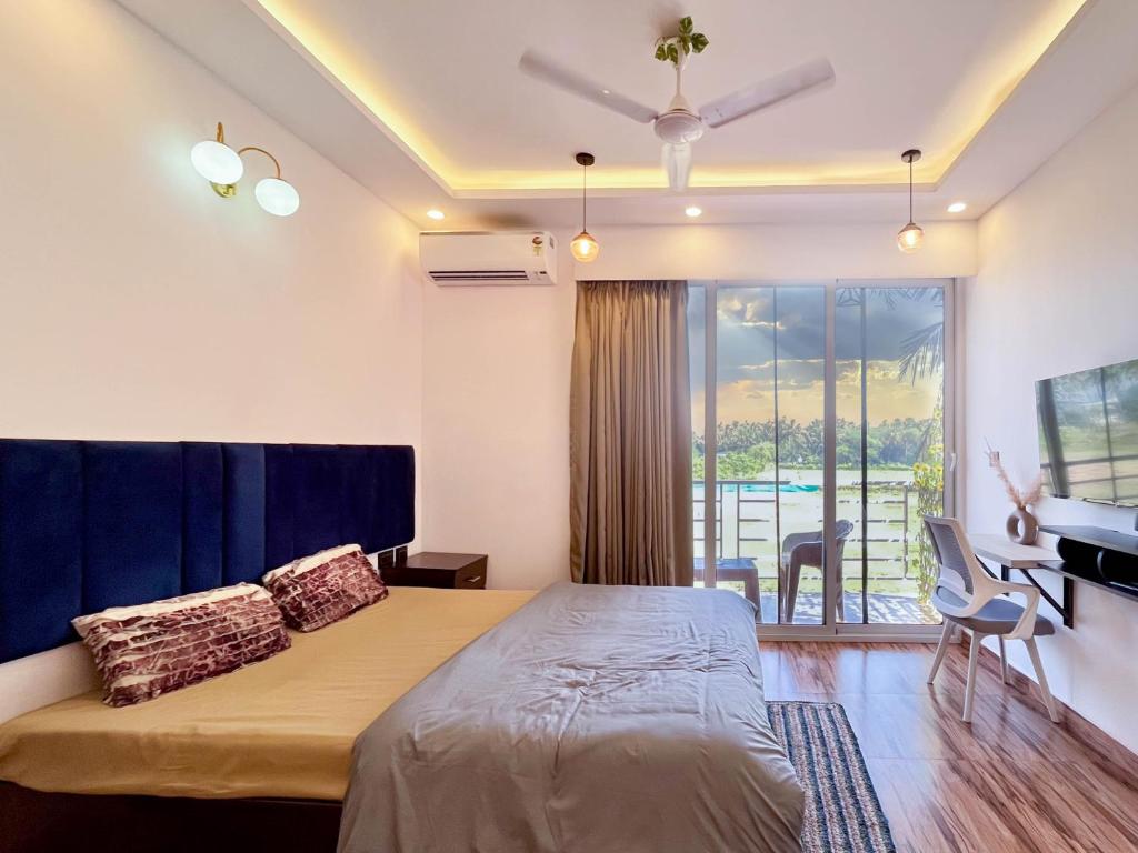 a bedroom with a large bed and a balcony at Luxury Apartment With Farm View in Siolim