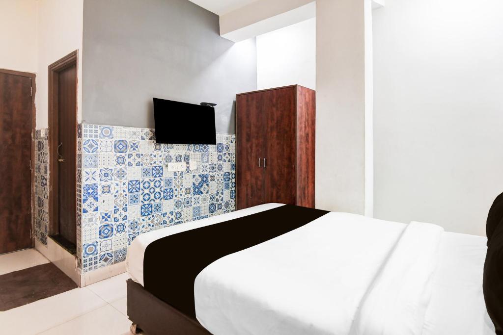 a bedroom with a bed and a tv on a wall at Hotel O CITY INN in Kolkata