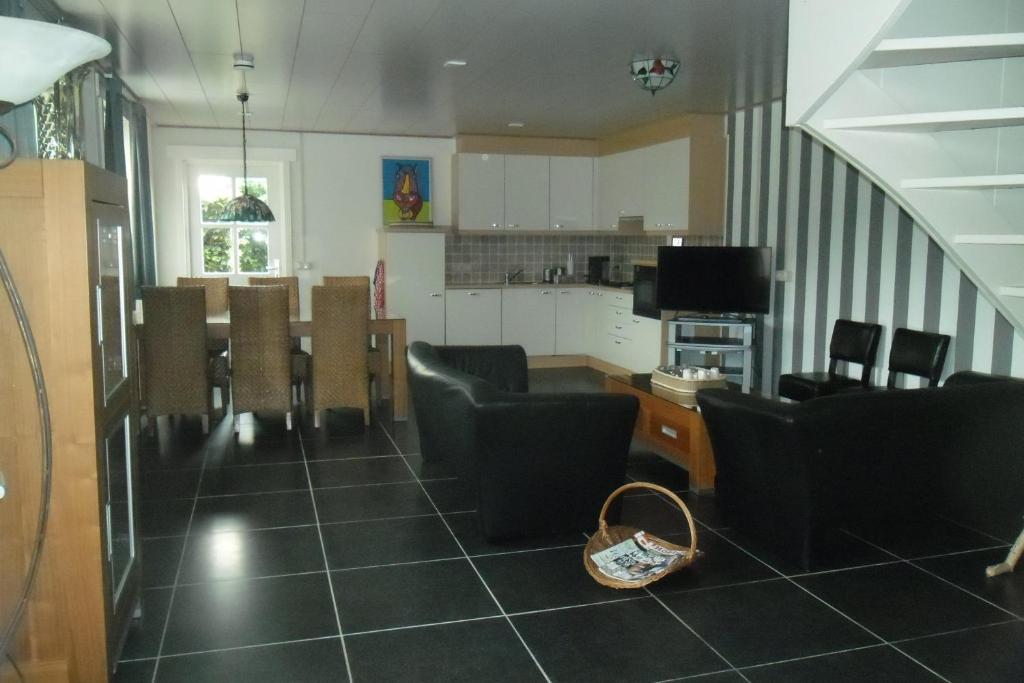 a living room with chairs and a table and a kitchen at Herkenhoek 3 bedroom apartement in Heeswijk-Dinther