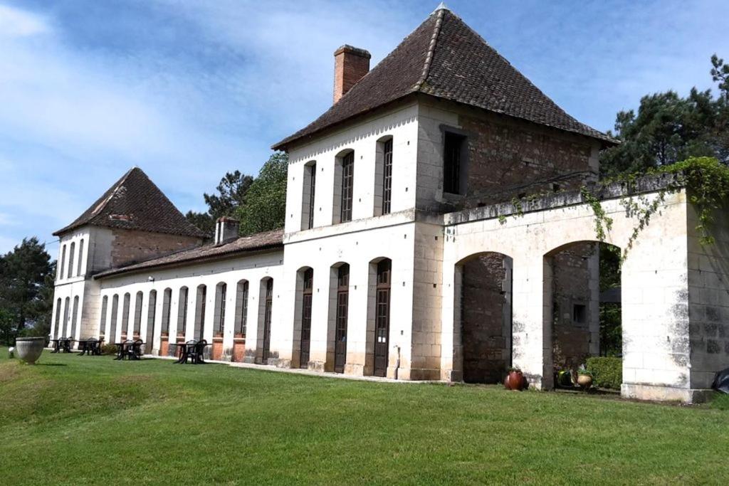 ein großes Backsteingebäude mit einem großen Rasenplatz in der Unterkunft Château Neuf Le Désert in Le Pizou