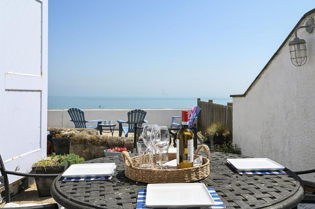 a table with a bottle of wine and glasses on it at Driftwood Cottage by Bloom Stays in Folkestone