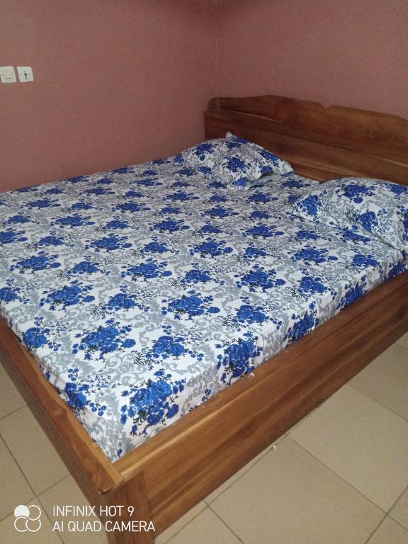 a bed with a blue and white comforter on it at Hôtel Maximum in Agbézourhlan