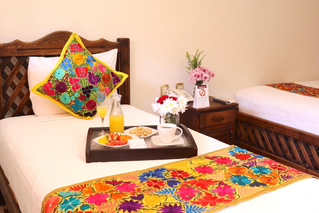 a hotel room with two beds with a tray of food at Camino Mexicano Hotel & Resort in Tuxtla Gutiérrez