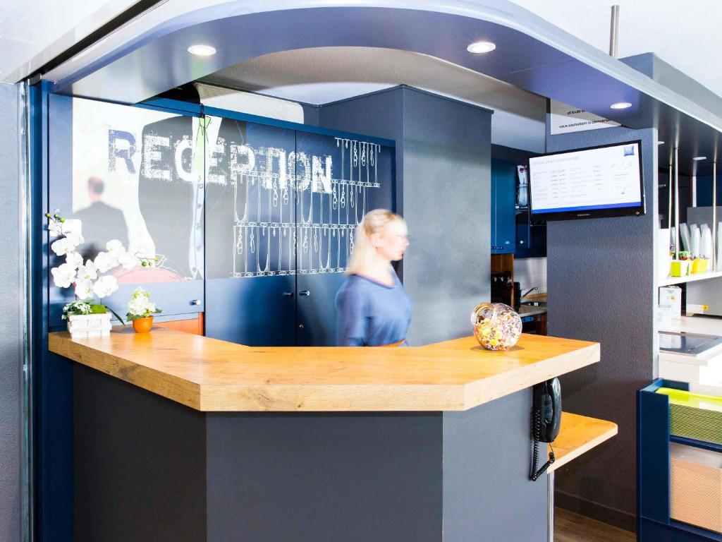 a reception counter in an office with blue walls at Ibis Budget Marmande in Marmande