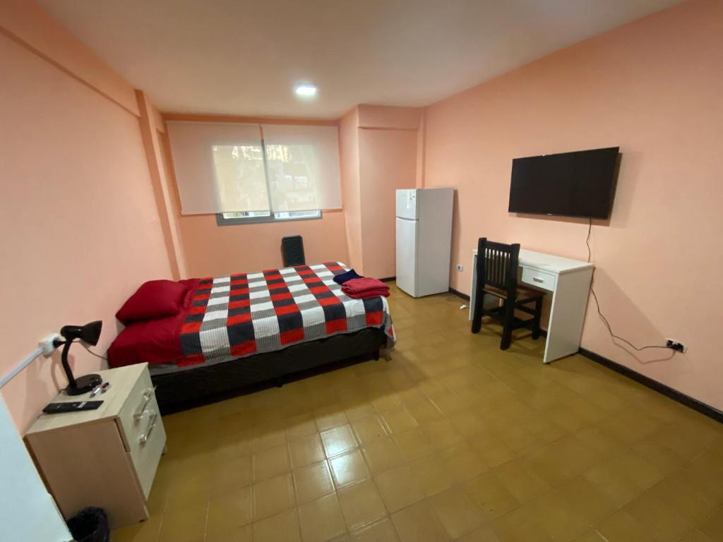 a bedroom with a bed and a desk and a tv at Candil in Neuquén