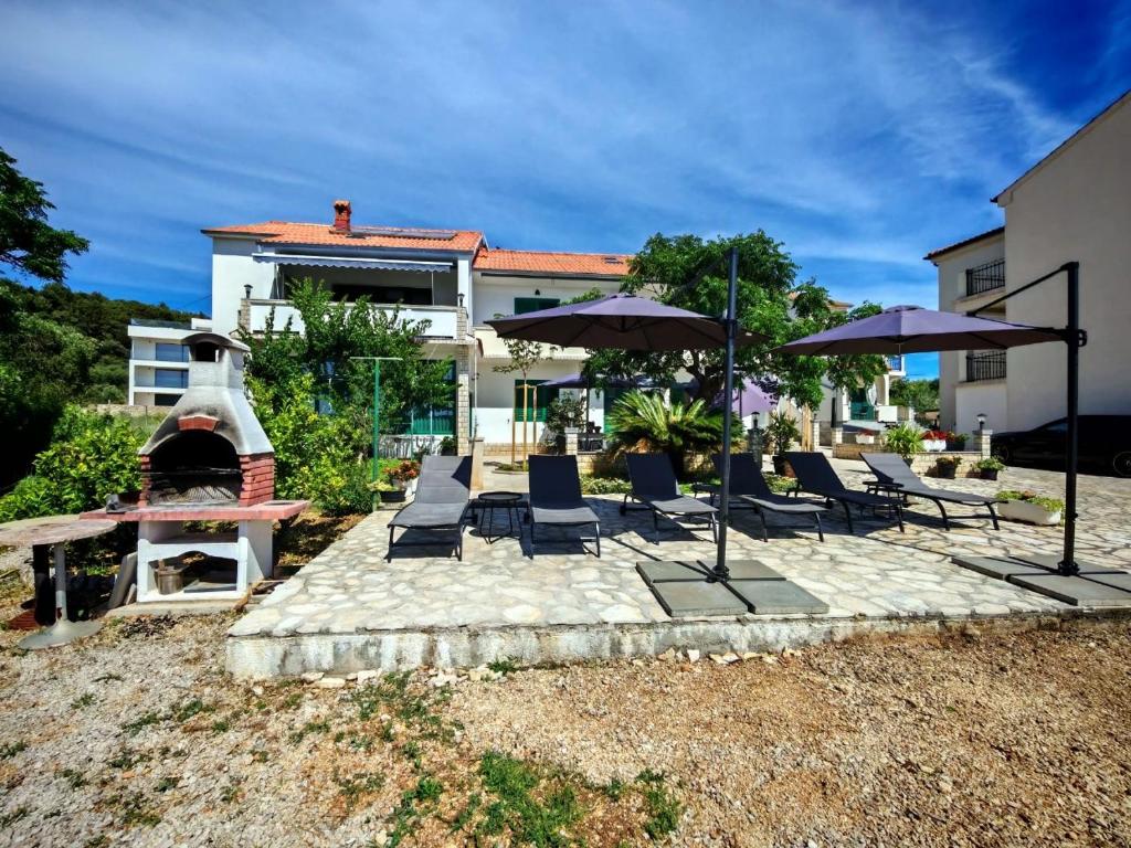 a group of chairs and umbrellas in front of a house at Room`s Brica in Barbat na Rabu