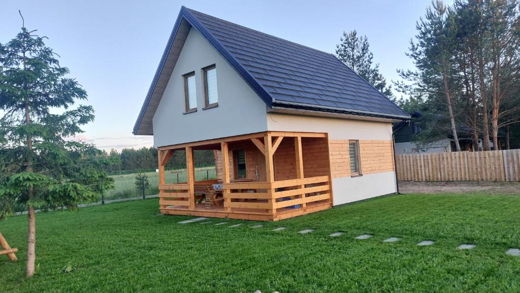 a small house with a gambrel roof on a lawn at Dom nad jeziorem Serwy in Serwy