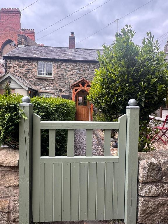 a green fence in front of a house at Abbey Cottage in Llangollen