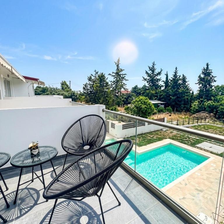 a balcony with a table and chairs and a swimming pool at Piscina Mare #PROPERTLY in Nea Kallikrateia