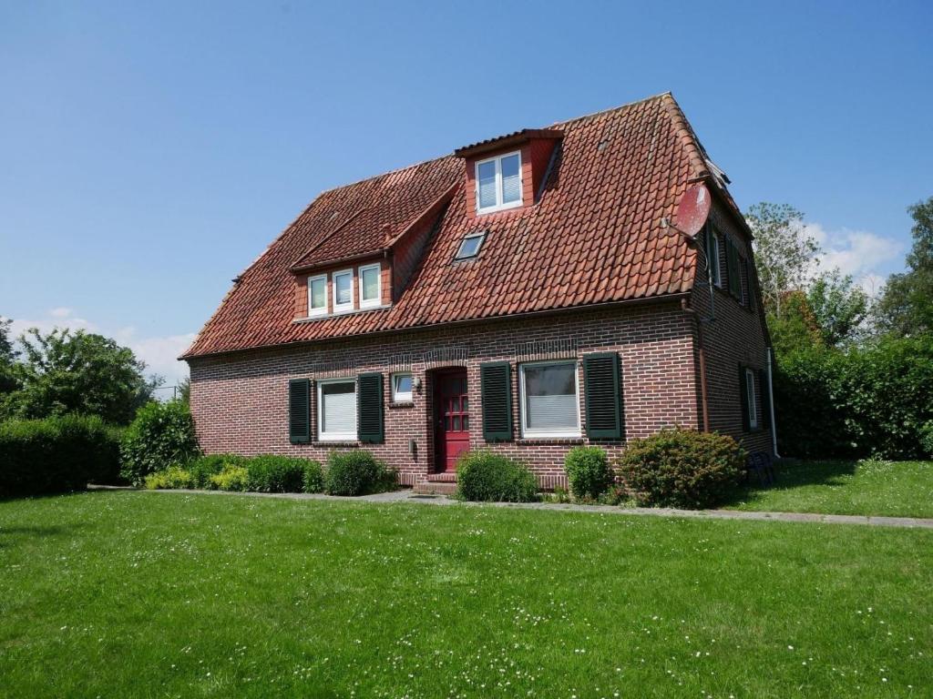 a house with a red roof on a green lawn at Heringsmoewe in Tossens