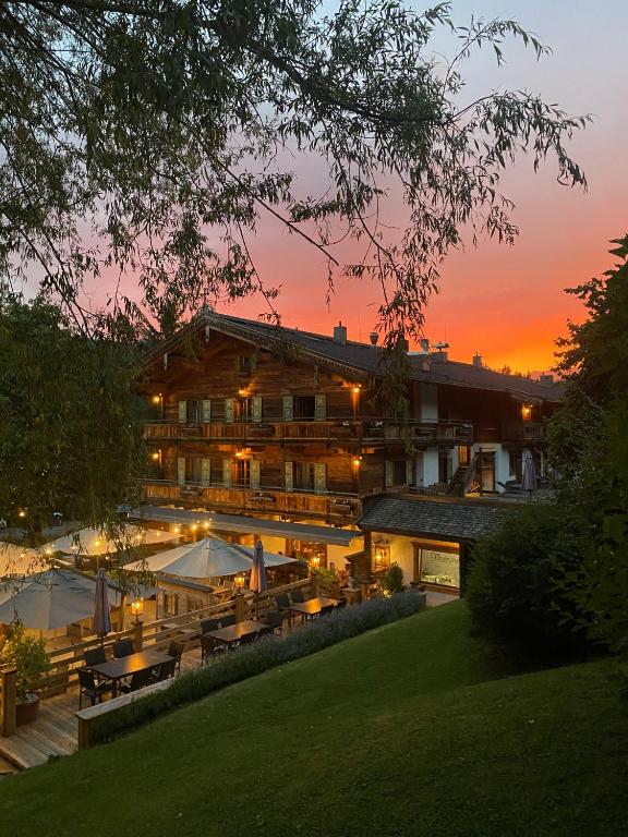 a hotel with tables and umbrellas at sunset at Landhotel Vordergrub in Kitzbühel