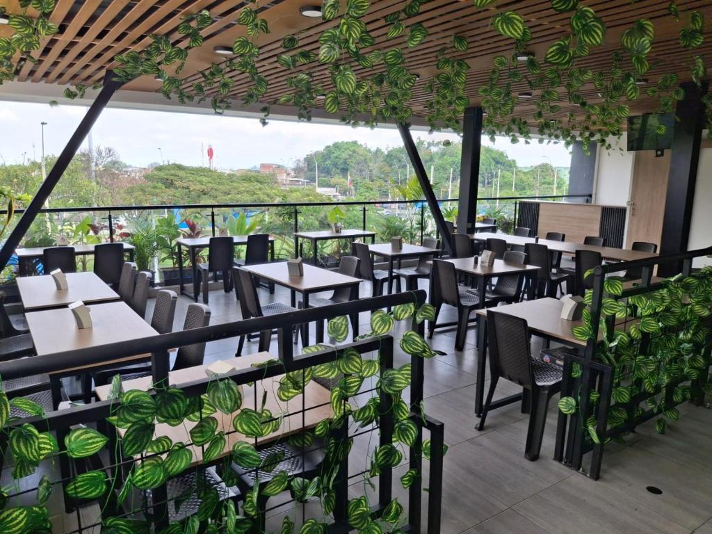 a restaurant with tables and chairs and plants at Hotel Brisas De Calima in Cali