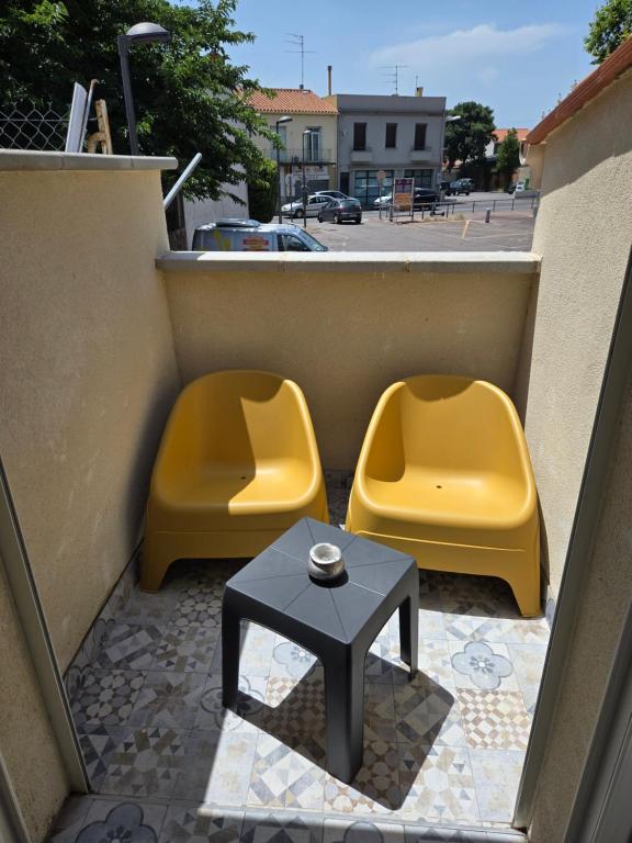 two yellow chairs and a table on a balcony at small and cozy in Perpignan