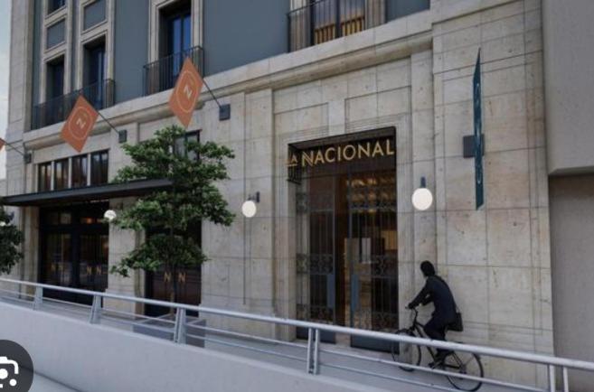 Ein Mann fährt mit dem Fahrrad vor einem Macyml-Gebäude in der Unterkunft Chihuahua Historic Suite in Chihuahua