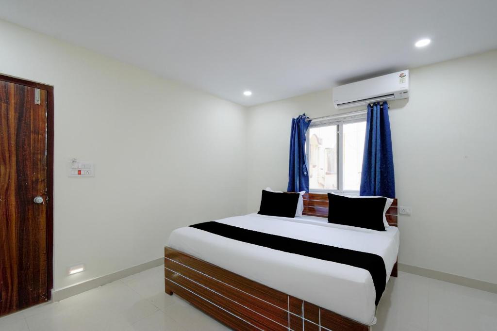 a bedroom with a bed with blue curtains and a window at Hotel O Sree Nirvi in Ameerpet