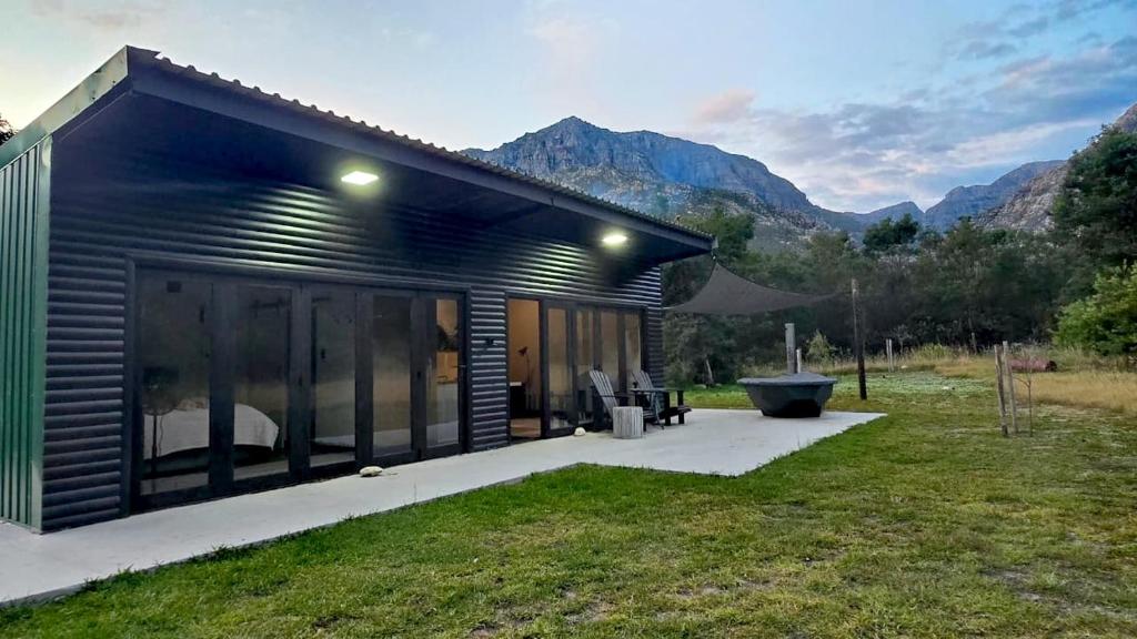 a small black house with mountains in the background at Tranquility - Cabin nestled in the mountains in Worcester