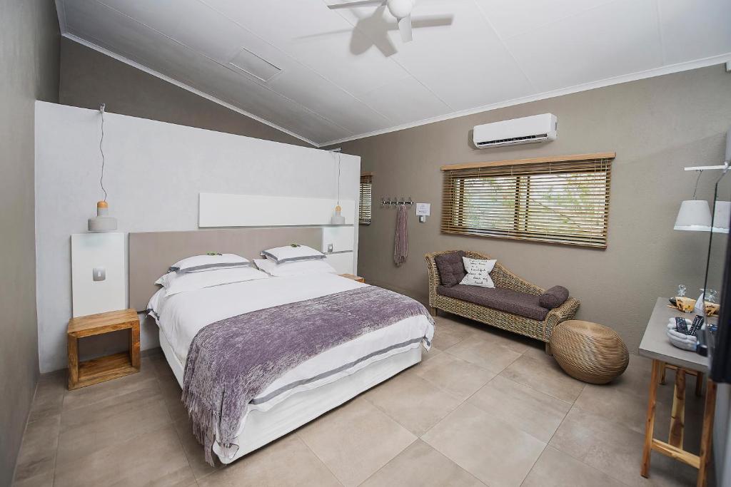a bedroom with a large bed and a chair at Birds Babble Self Catering in Nelspruit