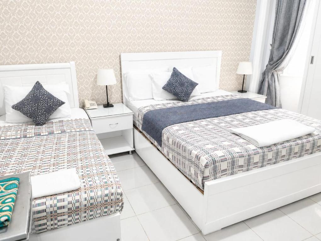 a white bedroom with two beds and two lamps at new colmbia in Cairo