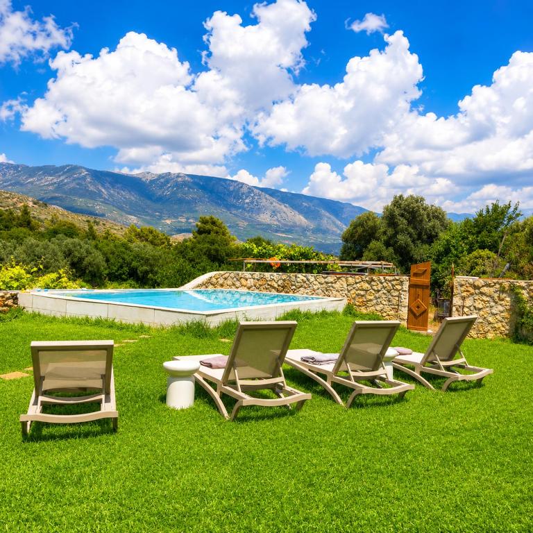 a group of lounge chairs in the grass near a swimming pool at Endless Green Villa in Argostoli