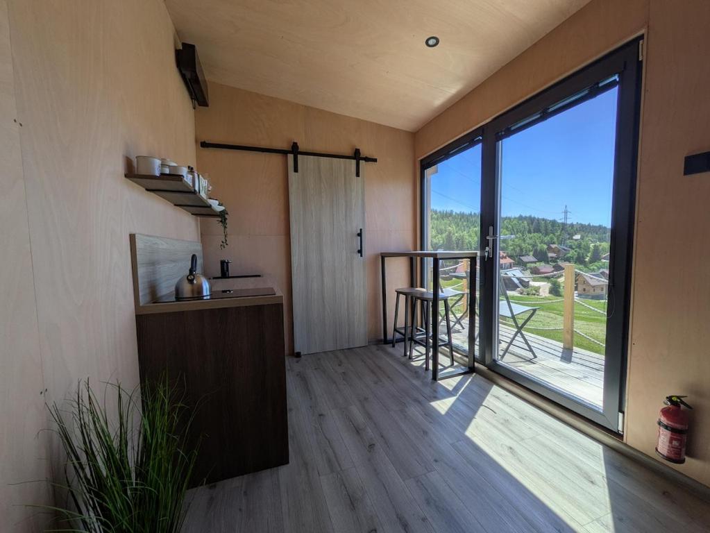 a room with a large window and a kitchen with a view at Tiny House Dedinky in Dedinky