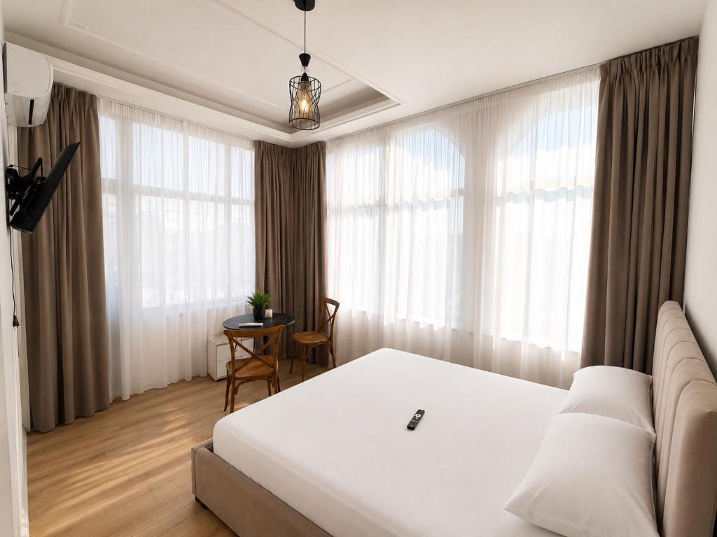 a bedroom with a white bed and a table at Hotel Danja in Laç