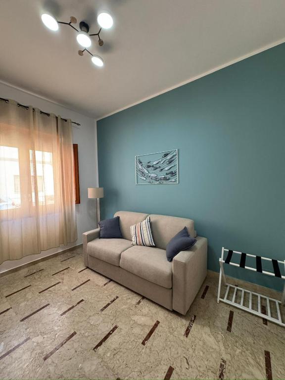 a living room with a couch and a blue wall at La casa di GiòGiò in San Vito lo Capo