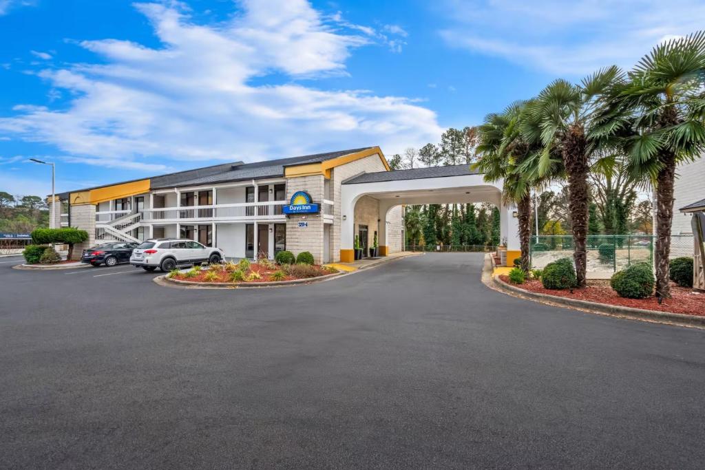 a hotel with a parking lot and palm trees at Days Inn by Wyndham Raleigh Midtown in Raleigh