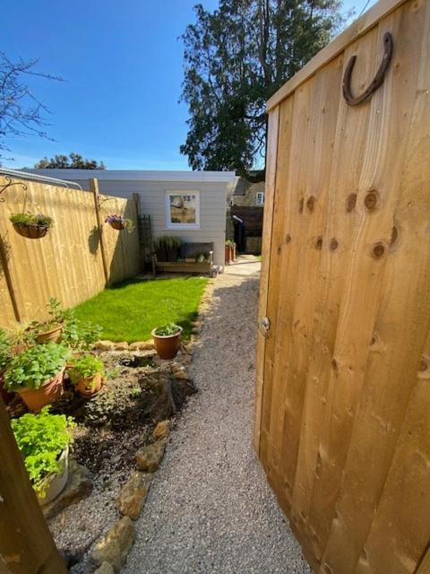 a wooden fence next to a yard with potted plants at The Rest-Well Lodge in Sherborne