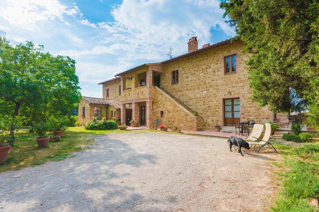 duży ceglany dom z psem stojącym przed nim w obiekcie Agriturismo Podere San Gregorio w mieście Pienza