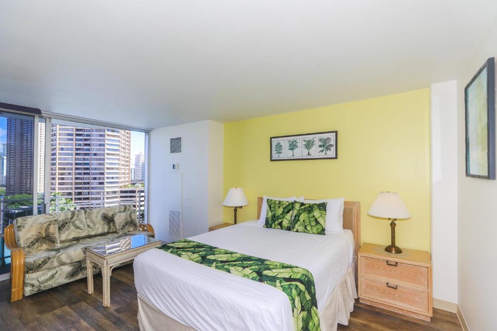 a bedroom with a bed and a couch and a window at Ilikai Marina 1285 in Honolulu