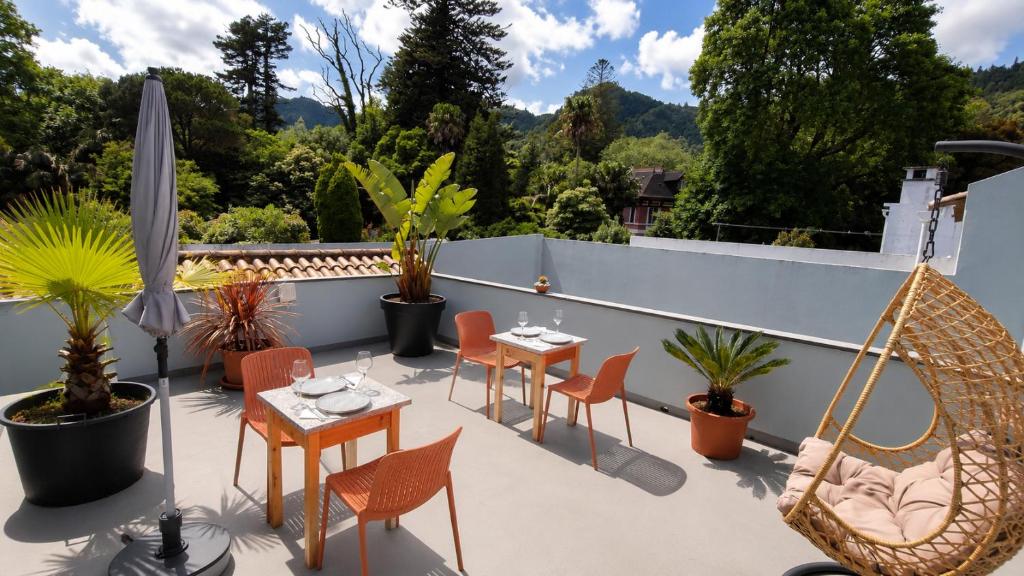 a patio with tables and chairs on a roof at Victória Guest House in Furnas