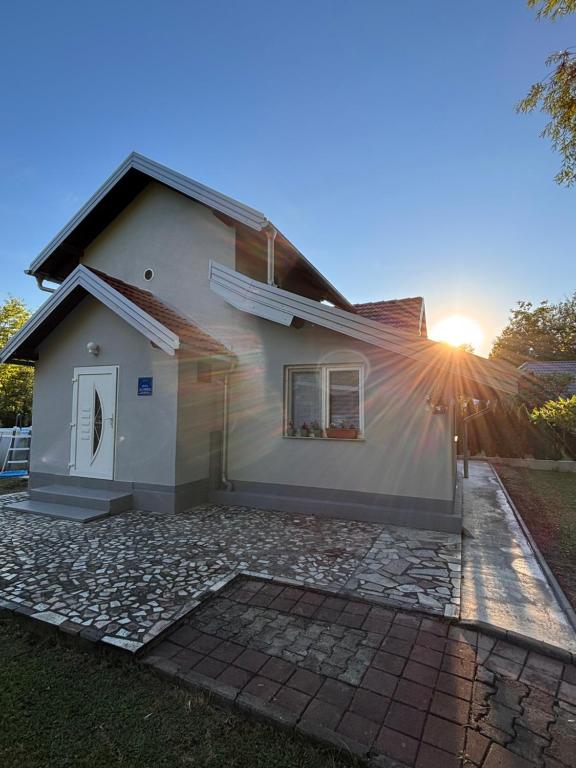 a white house with the sun setting behind it at Kuca Delić in Račić