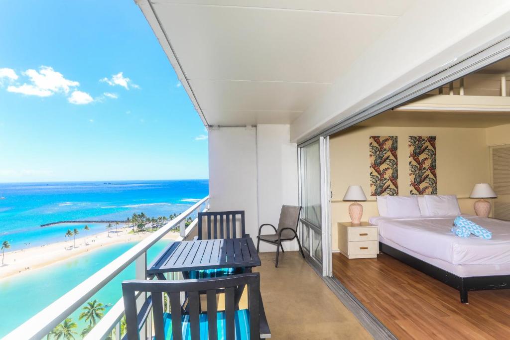 a bedroom with a bed and a balcony with the beach at Ilikai Tower 1842 in Honolulu