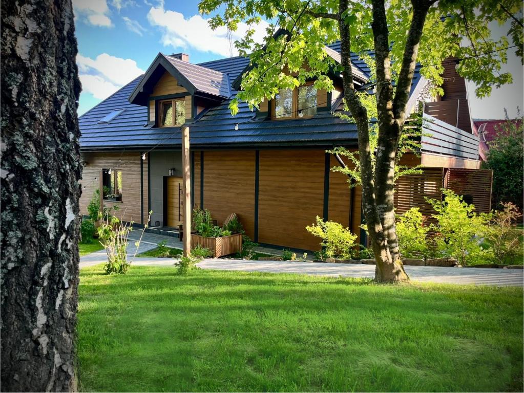 a house with a blue roof and a tree at Donikąd in Wetlina