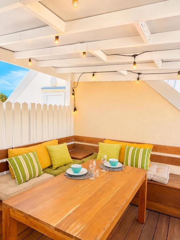 a living room with a wooden table and yellow pillows at Studio Coconut in Baie Nettle