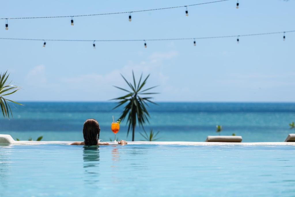 a woman in a swimming pool with a drink at Hurricane Jeri in Jericoacoara