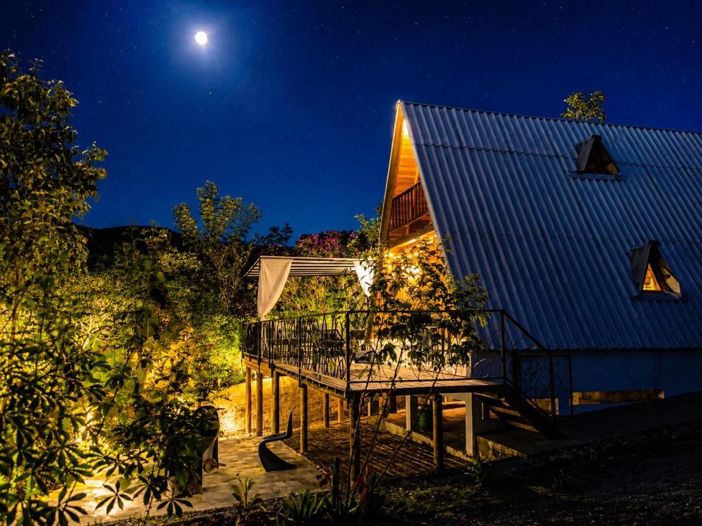 a house with a deck at night at Chalé Canto do Rio - Vale do Capão in Palmeiras