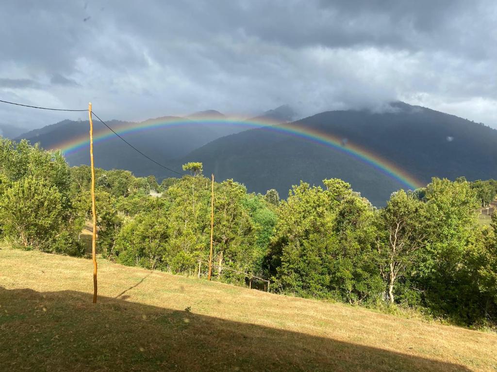 a rainbow in the middle of a field with trees at Cabaña Bellavista in Cochamó