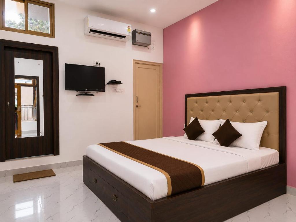 a bedroom with a large bed with a pink wall at Hotel Eva Palace in Chatra