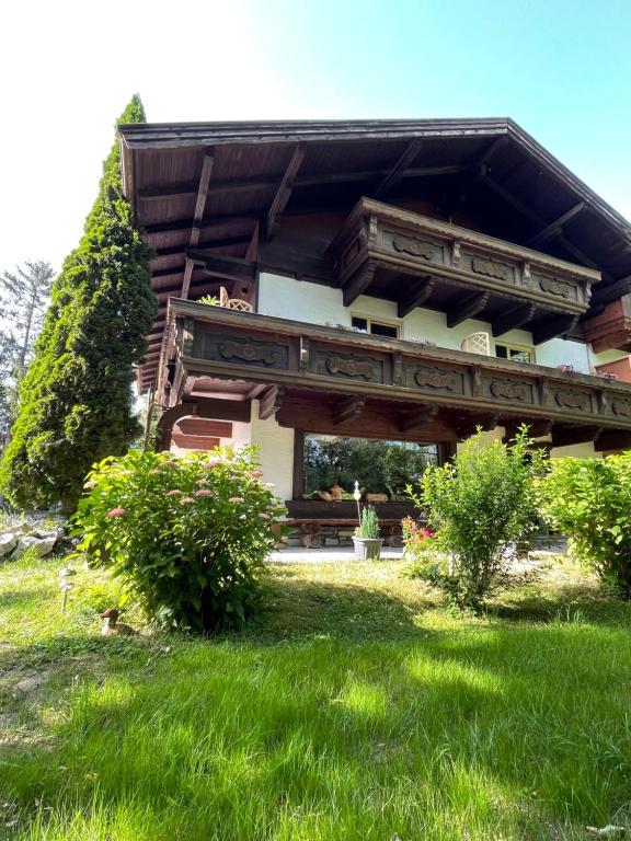 a building with a porch and green grass at Haus am Bach in Erl