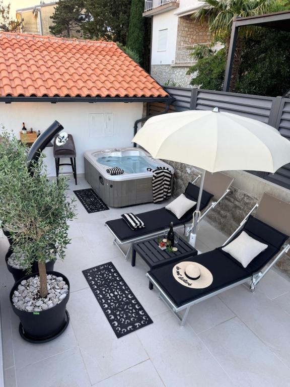 a patio with two chairs and an umbrella and a hot tub at Korina Suites - 2 appartments, 1 with jacuzzy in Dramalj