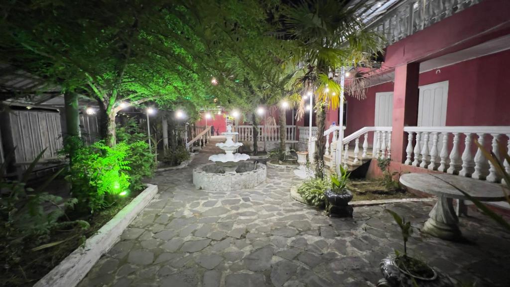 a courtyard at night with a fountain and trees at Ararat in Ozurgetʼi