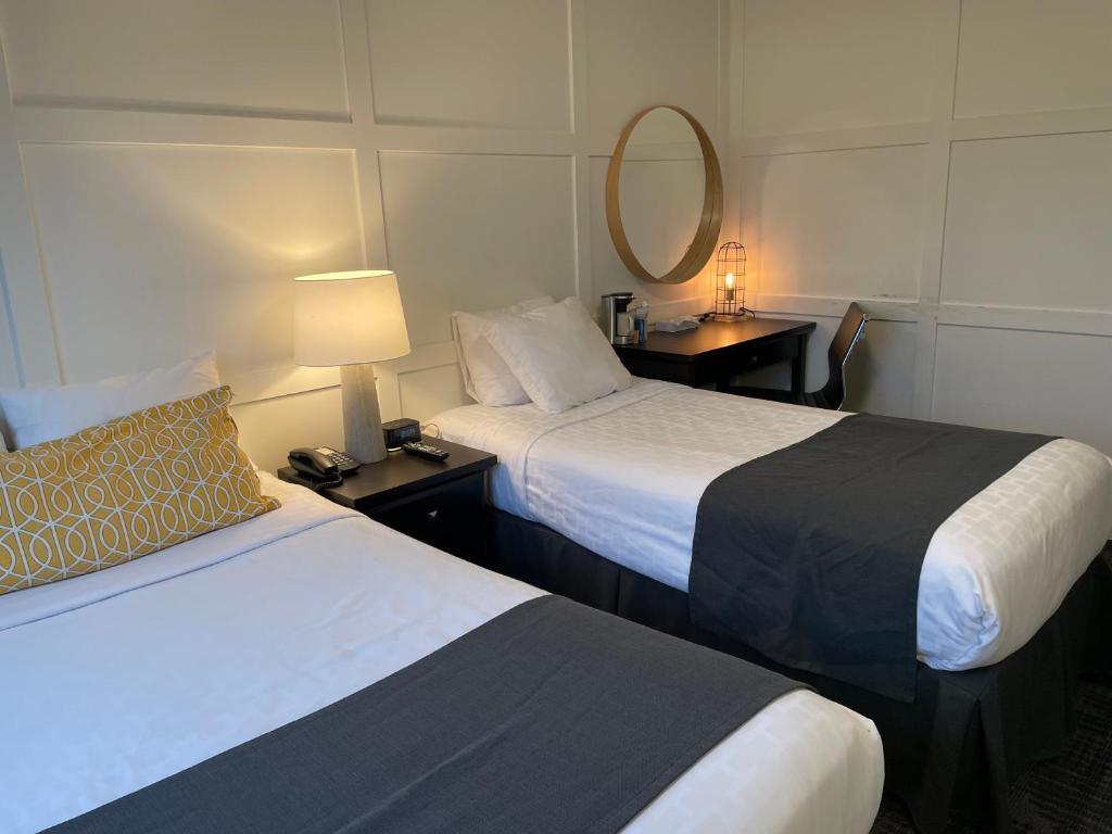 a hotel room with two beds and a mirror at Steveston Cafe & Hotel in Richmond