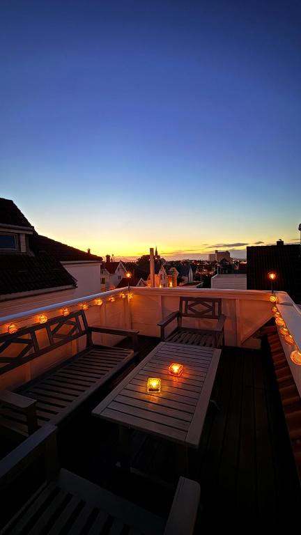 a rooftop patio with a table and lights at night at Asanzo Historic Attic-Traditional Norwegian Home & Warm Indian Hospitality in Stavanger