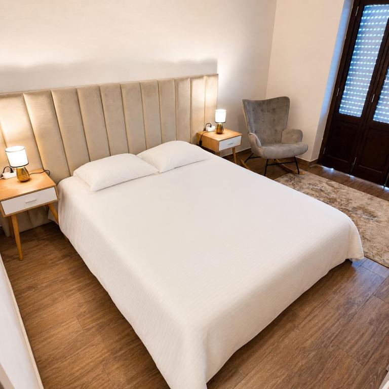 a bedroom with a large white bed and a chair at Albani Hostel in Palmela