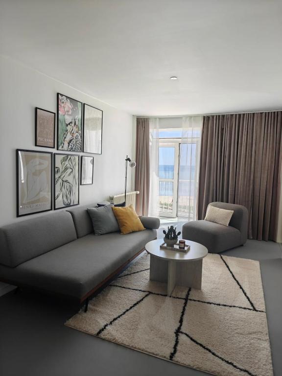 a living room with a couch and a table at Sea view Ella - Hejlsminde Badehotel in Hejlsminde
