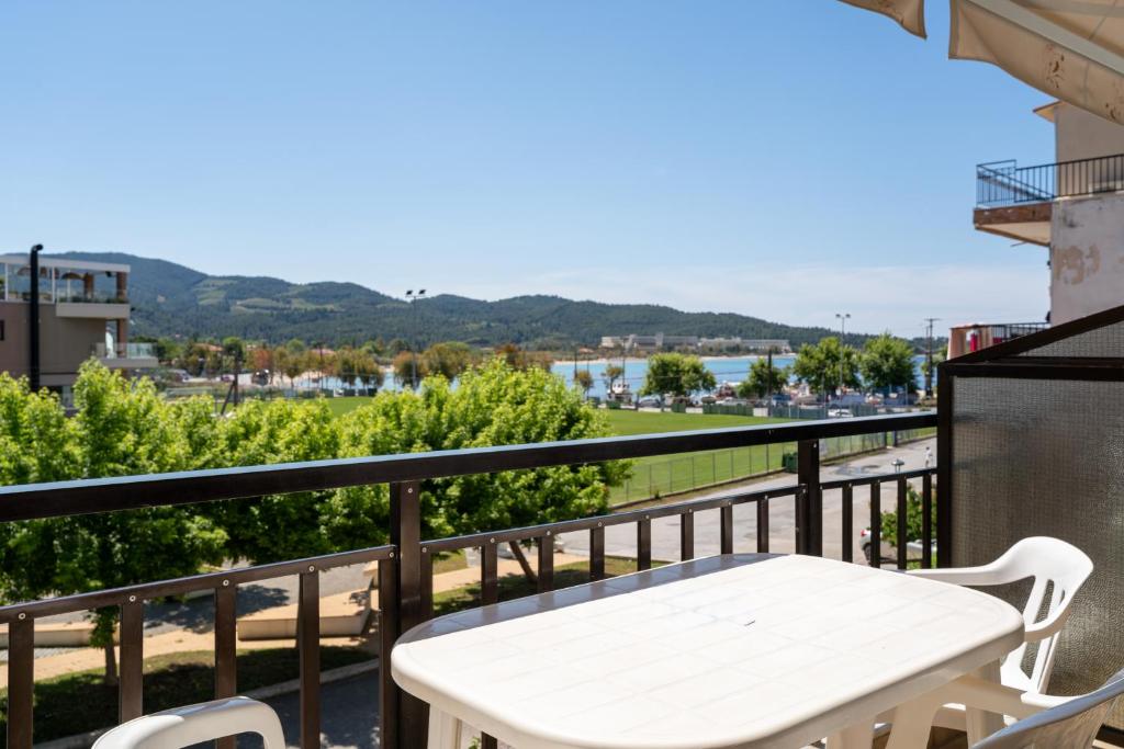 a white table on a balcony with a view of the water at Studios Vaso in Neos Marmaras