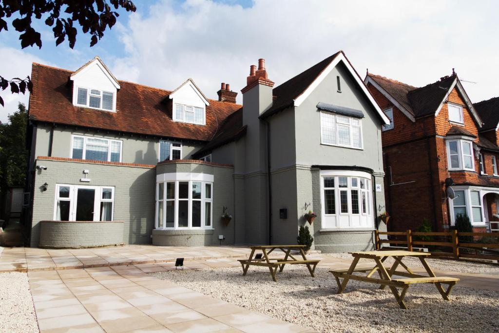 a house with two picnic tables in front of it at Rye Court Hotel in High Wycombe