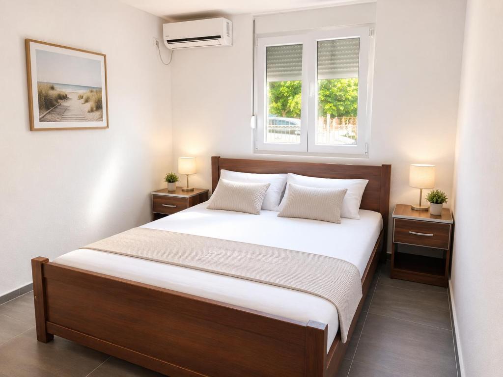 a bedroom with a bed with two night stands and two windows at Apartments Leyla in Ulcinj